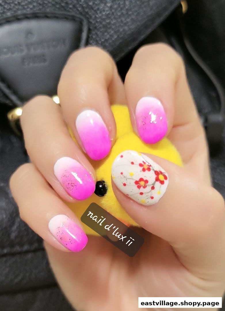 A hand showcases vibrant pink ombre nails with glitter, one featuring delicate floral art.