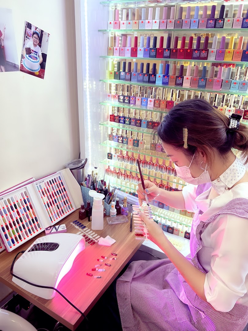 A nail technician meticulously paints nail samples, surrounded by a vibrant display of colorful nail polishes.