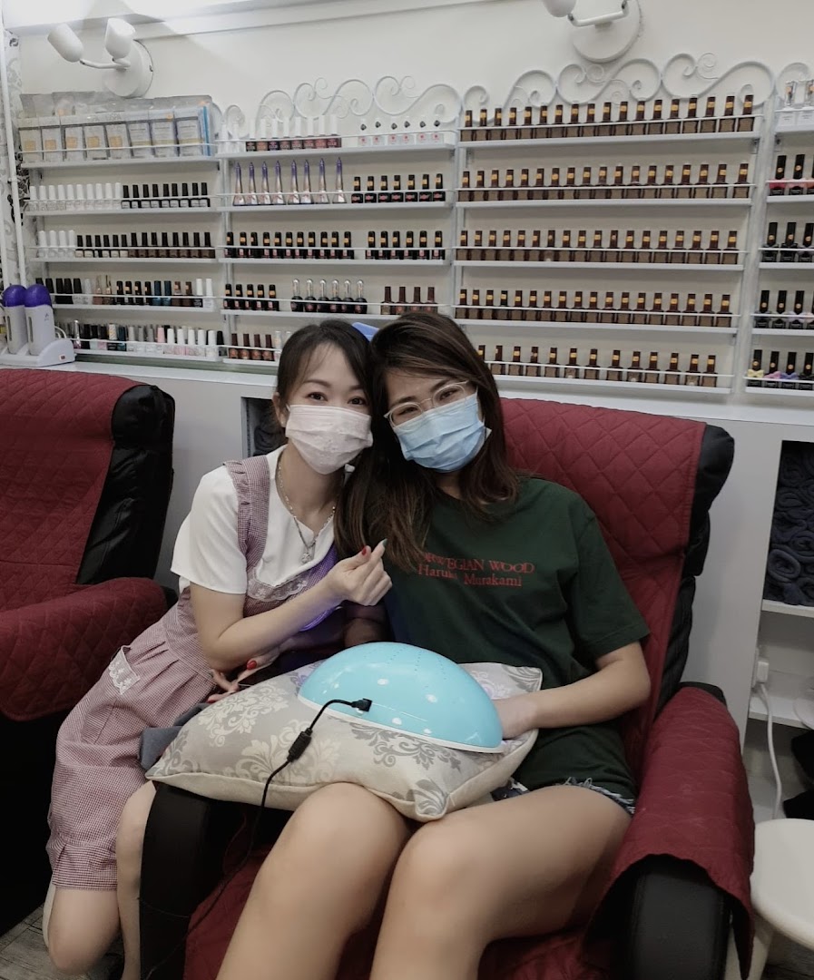 Two women, one a customer and one a technician, in a nail salon with polish displays.