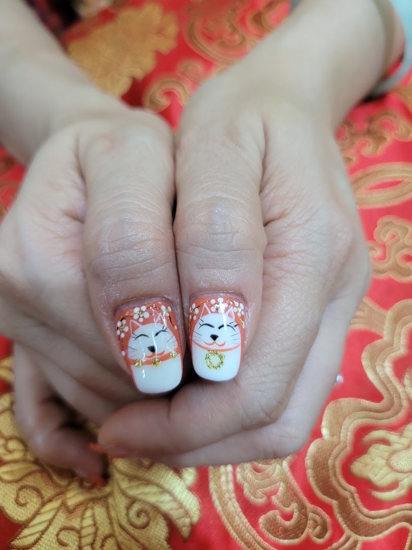Close-up of hands displaying intricate Maneki-neko cat nail art with gold accents.