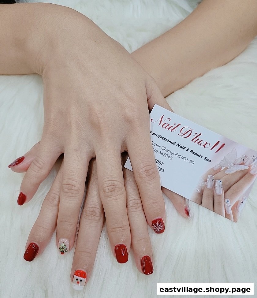 Hands showcasing festive red nail art with Santa, Christmas tree, and snowflake designs by NAIL DLUX II.