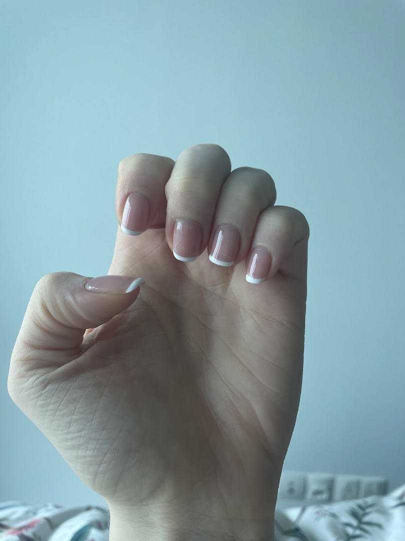 A hand showcasing a classic French manicure with clean white tips.