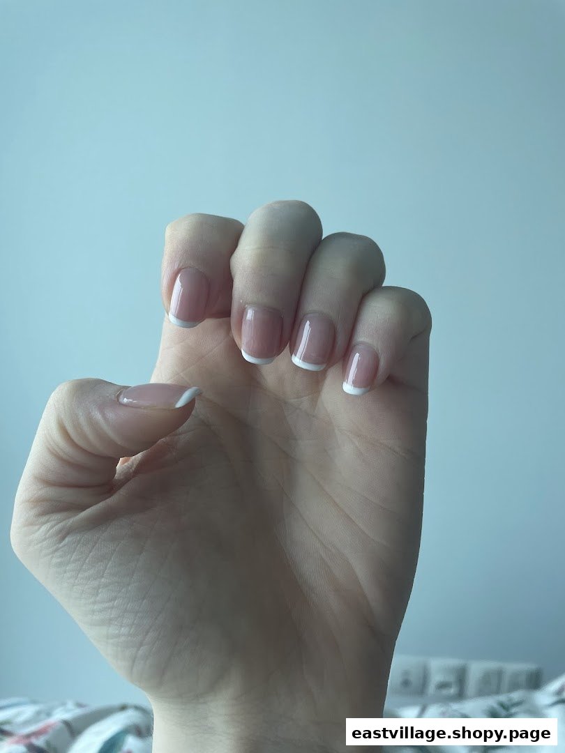 A hand showcasing a classic French manicure with clean white tips.