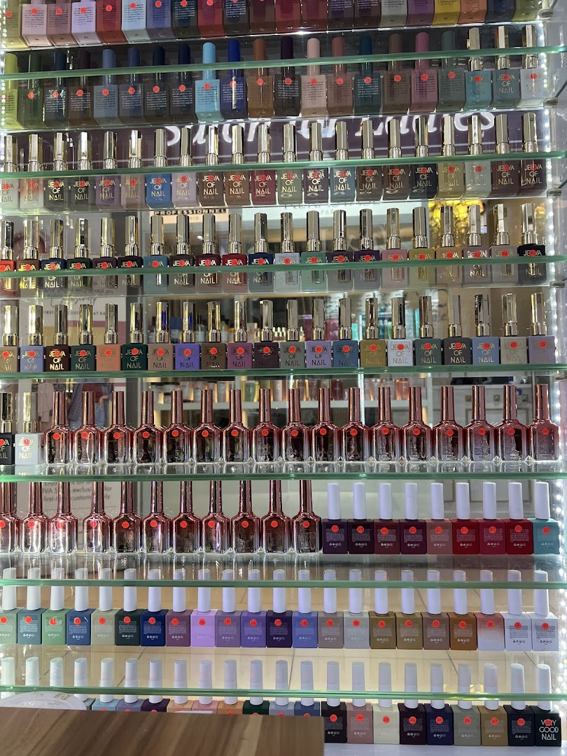 A vibrant display of numerous nail polish bottles arranged on illuminated glass shelves.
