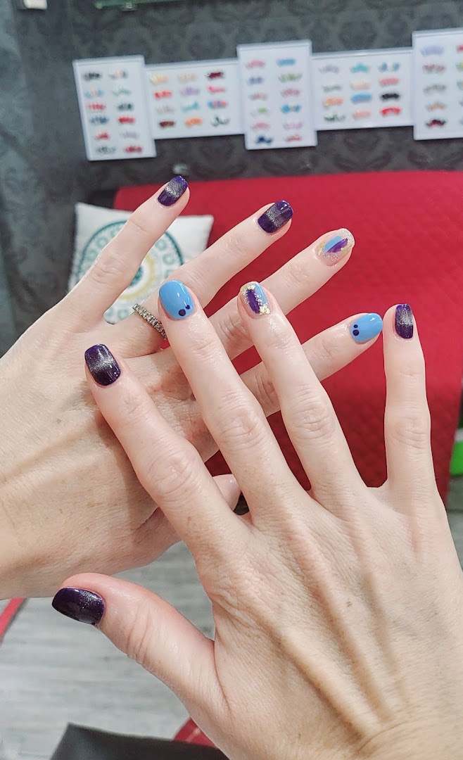 Close-up of two hands showcasing various vibrant and stylish manicured nail designs.