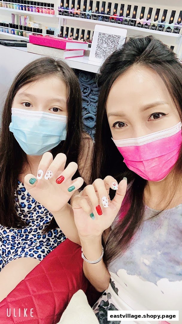 Two masked individuals proudly display their festive, freshly manicured nails inside a nail salon.
