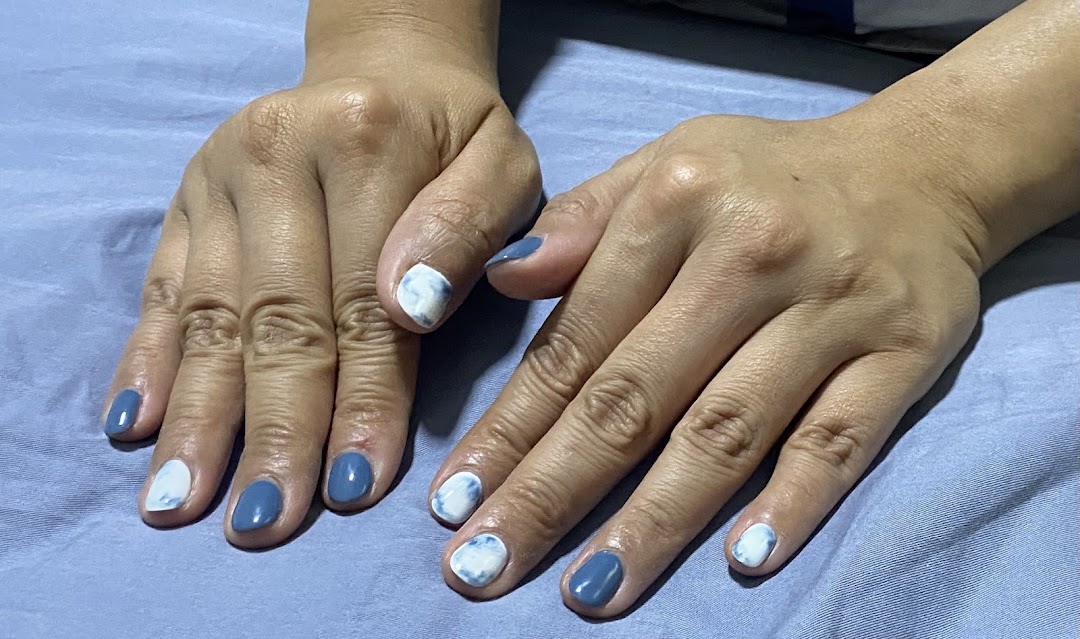 A person's hands displaying a fresh manicure with blue and white marbled nail polish.