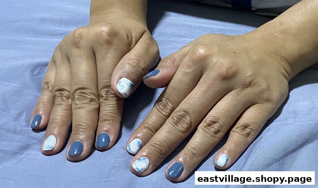 A person's hands displaying a fresh manicure with blue and white marbled nail polish.
