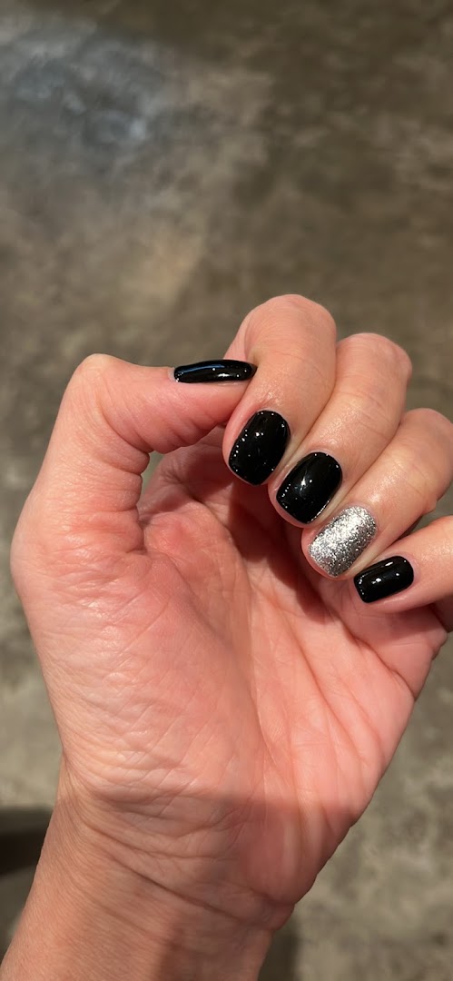 A hand displaying black and silver glitter nail polish, showcasing a finished manicure.