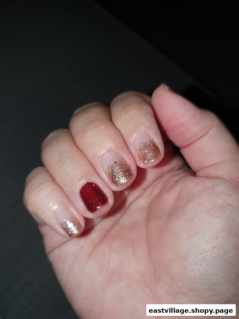 A hand showcasing a festive nail design with red and gold glitter polish.