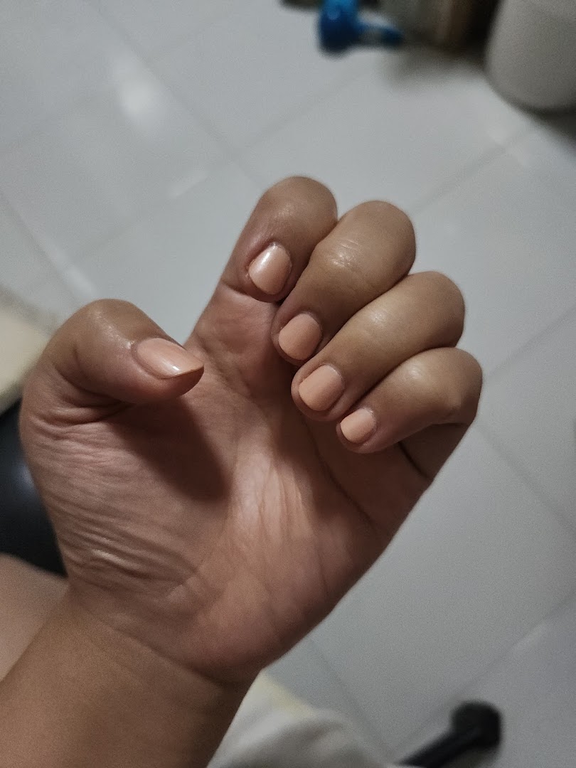 A close-up of a hand showcasing freshly manicured nails with a natural, peachy nude polish.