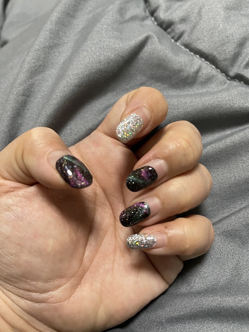 A hand showcasing nails with sparkling glitter and iridescent multi-chrome polish designs.