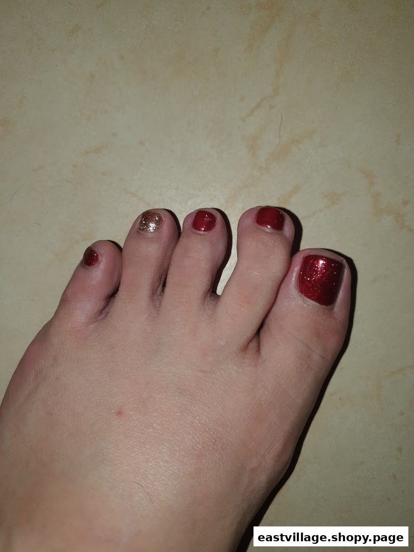 A close-up of a foot showcasing a festive red and gold glitter pedicure.