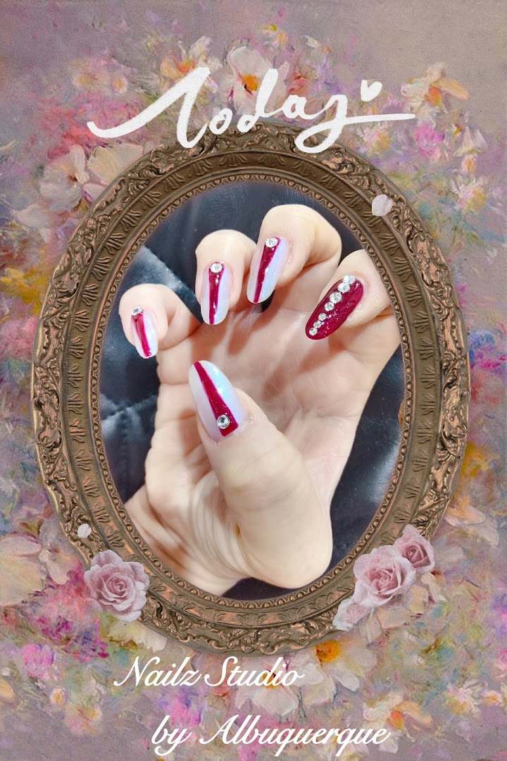 A hand showcasing elegant red and white nail art with rhinestone accents, framed by a decorative mirror.