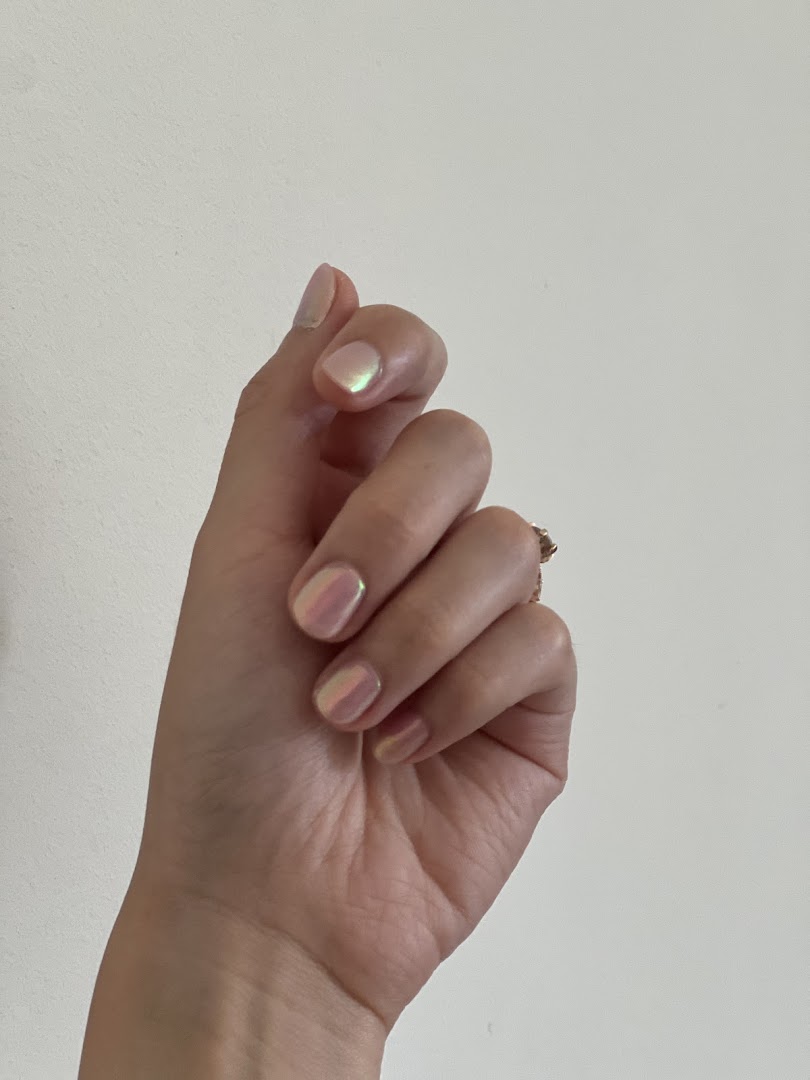 A hand showcasing iridescent, shimmery nail polish, highlighting a fresh manicure.