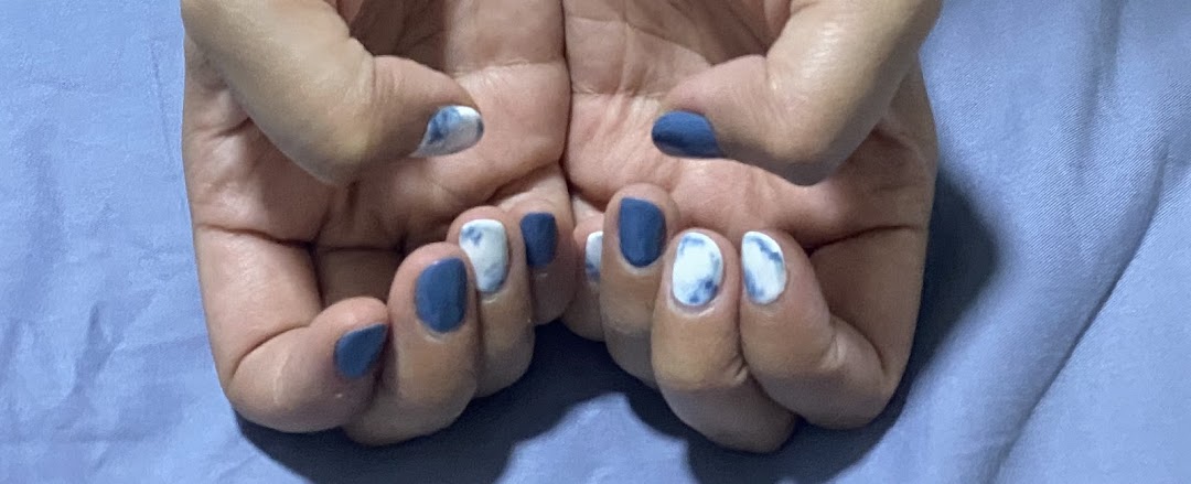 Close-up of hands showcasing a fresh manicure with blue and white marbled nail art.