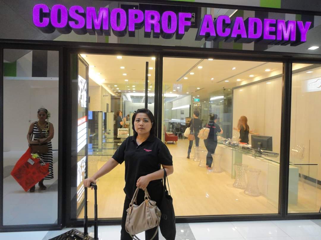 The glass entrance of a beauty establishment, with a prominent 'COSMOPROF ACADEMY' sign above, and people inside.