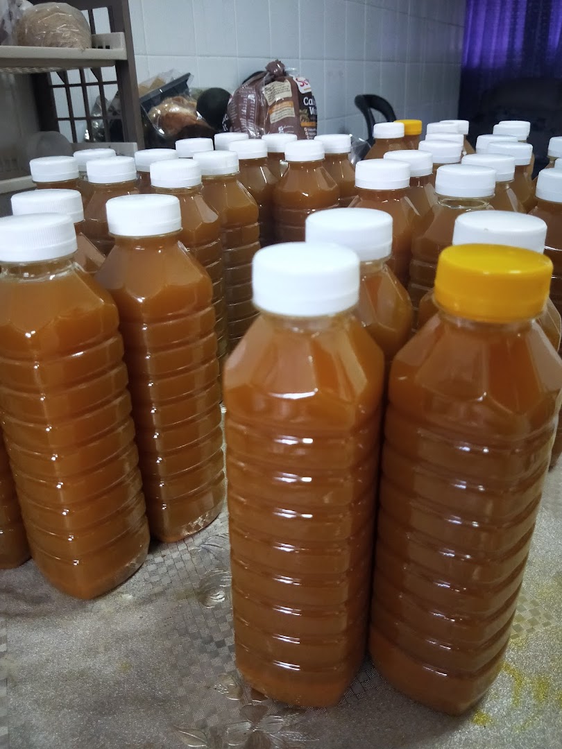 Numerous bottles filled with an amber liquid, possibly a wellness drink or product, are arranged on a surface.