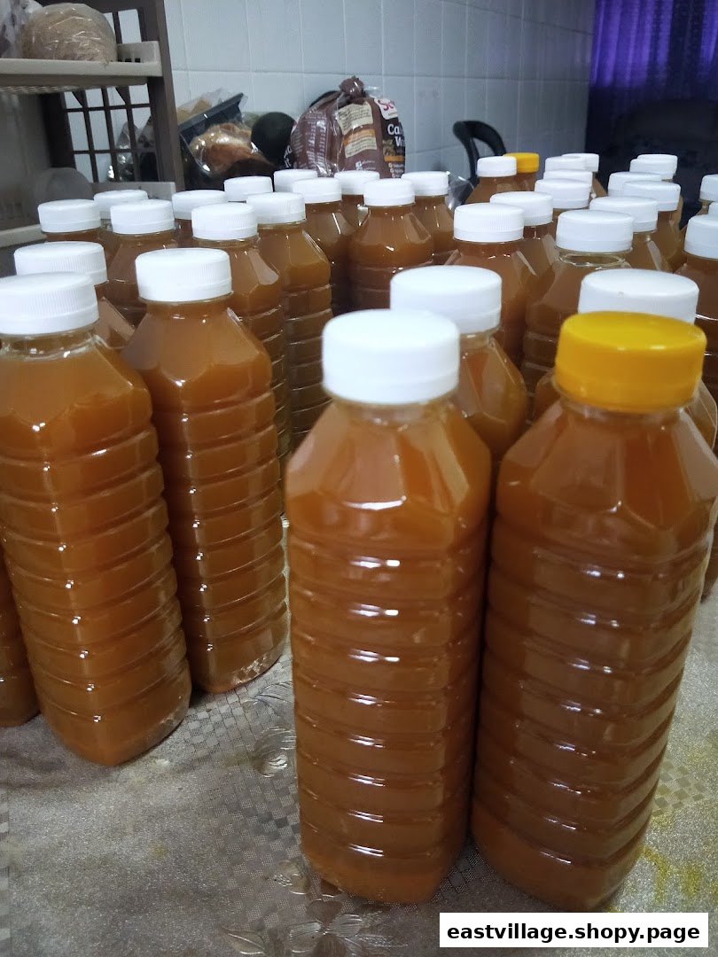 Numerous bottles filled with an amber liquid, possibly a wellness drink or product, are arranged on a surface.