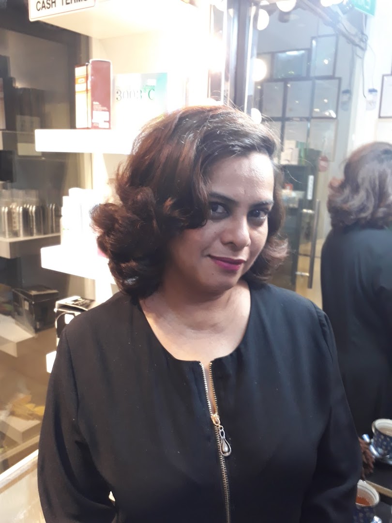 A woman with freshly styled hair smiling inside a beauty salon, showcasing salon services.