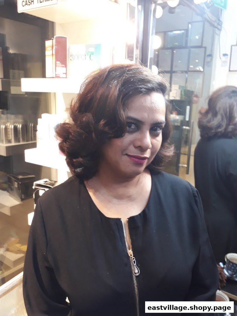 A woman with freshly styled hair smiling inside a beauty salon, showcasing salon services.