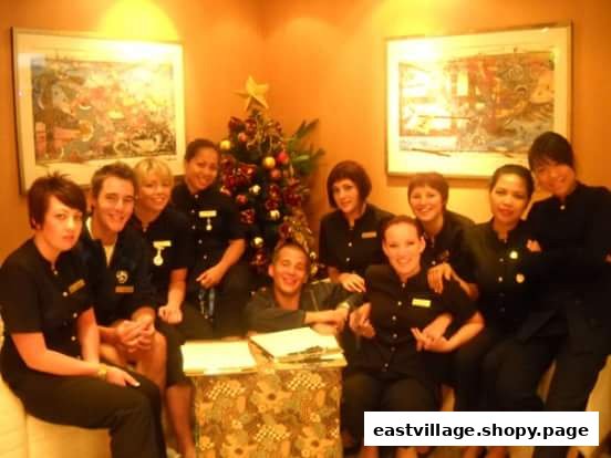A group of smiling salon staff members gathered around a table with a festive Christmas tree.
