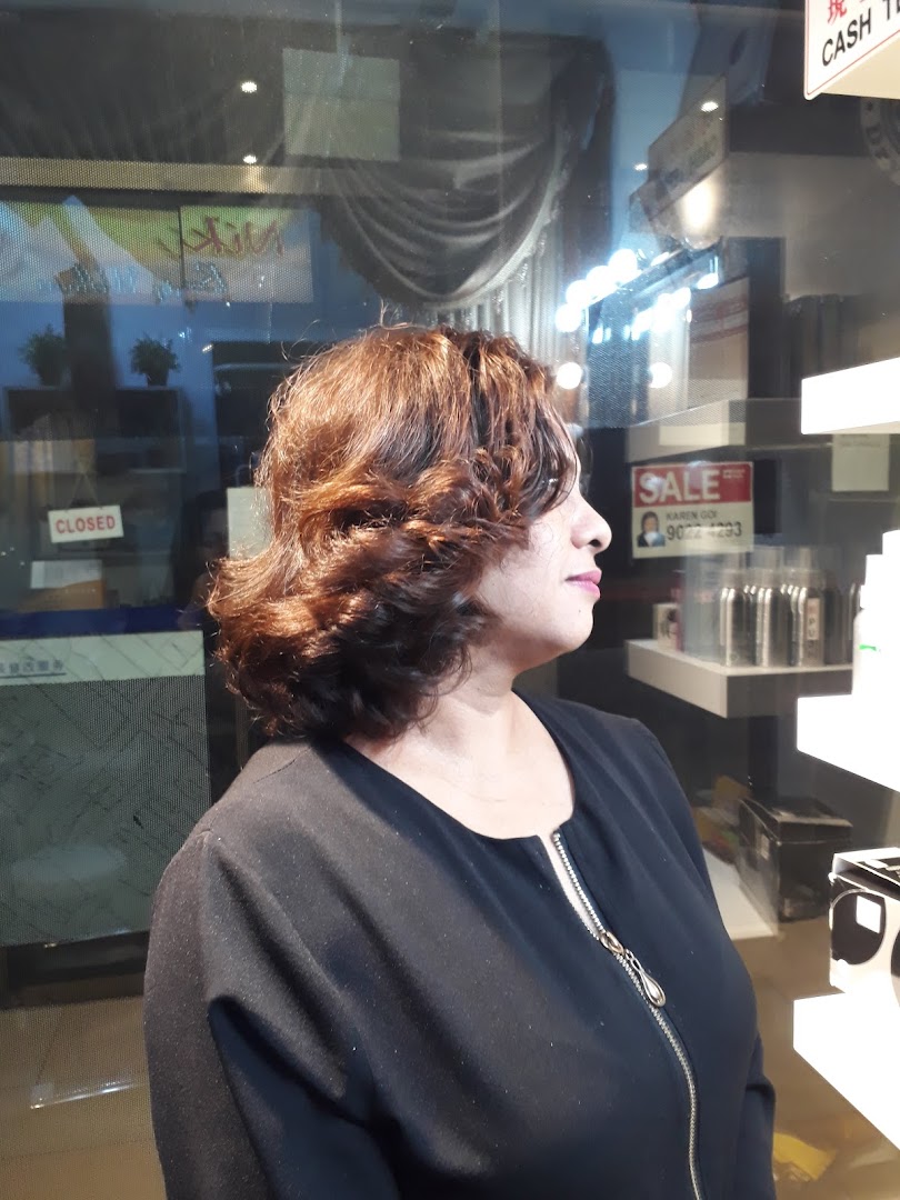 A woman with freshly styled, voluminous brown hair, likely a client at the salon.