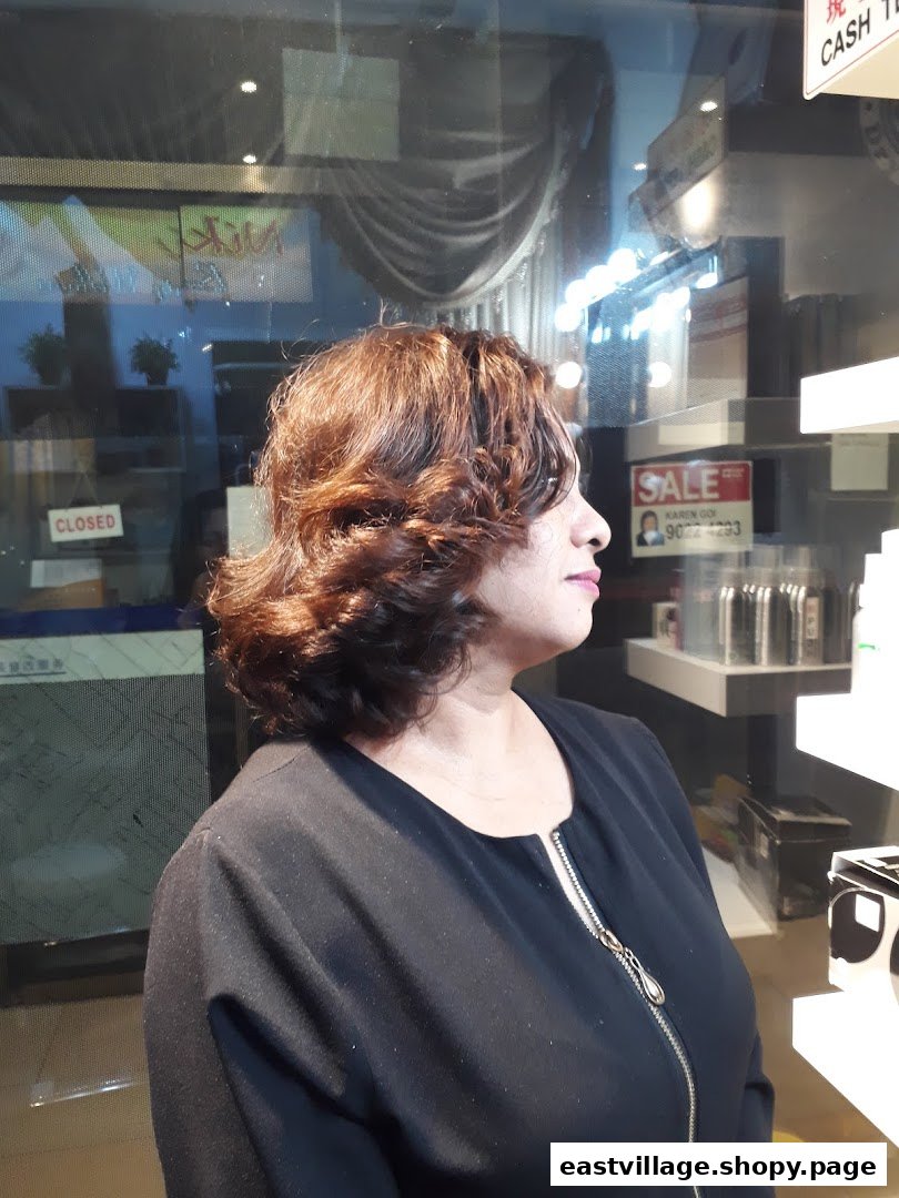 A woman with freshly styled, voluminous brown hair, likely a client at the salon.