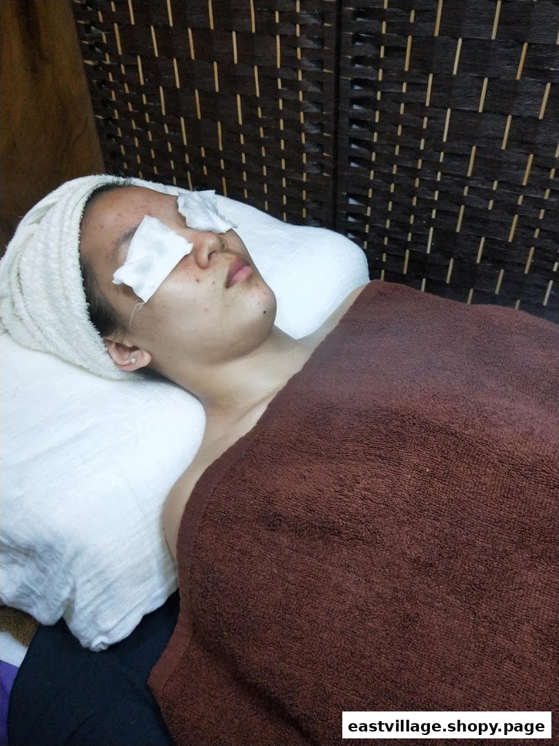 A woman relaxing during a beauty treatment with cotton pads over her eyes at Niki Beauty Wellness.