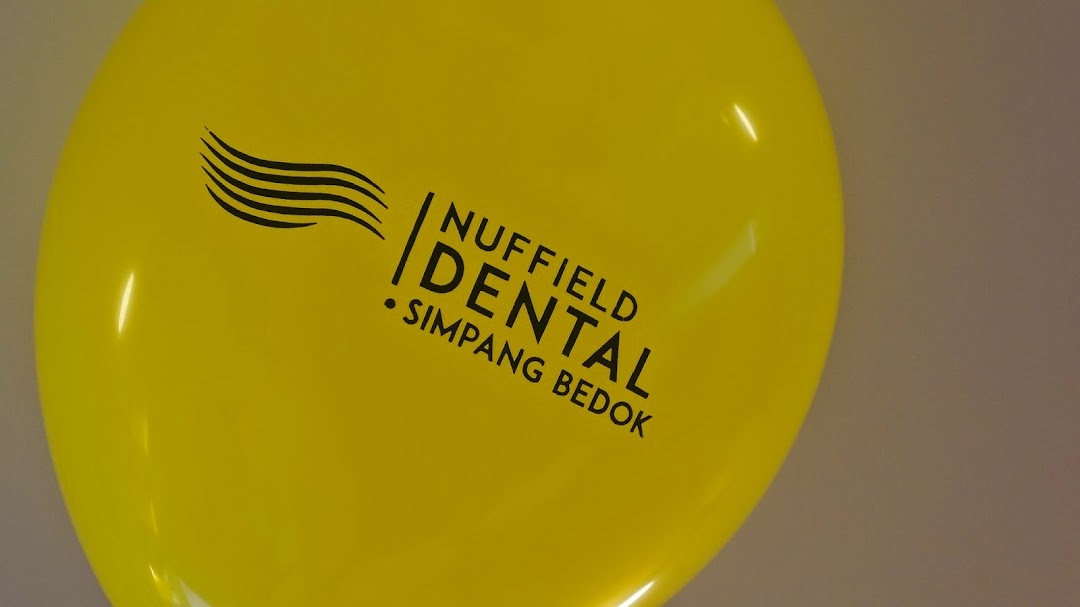 A bright yellow balloon featuring the Nuffield Dental Simpang Bedok logo.