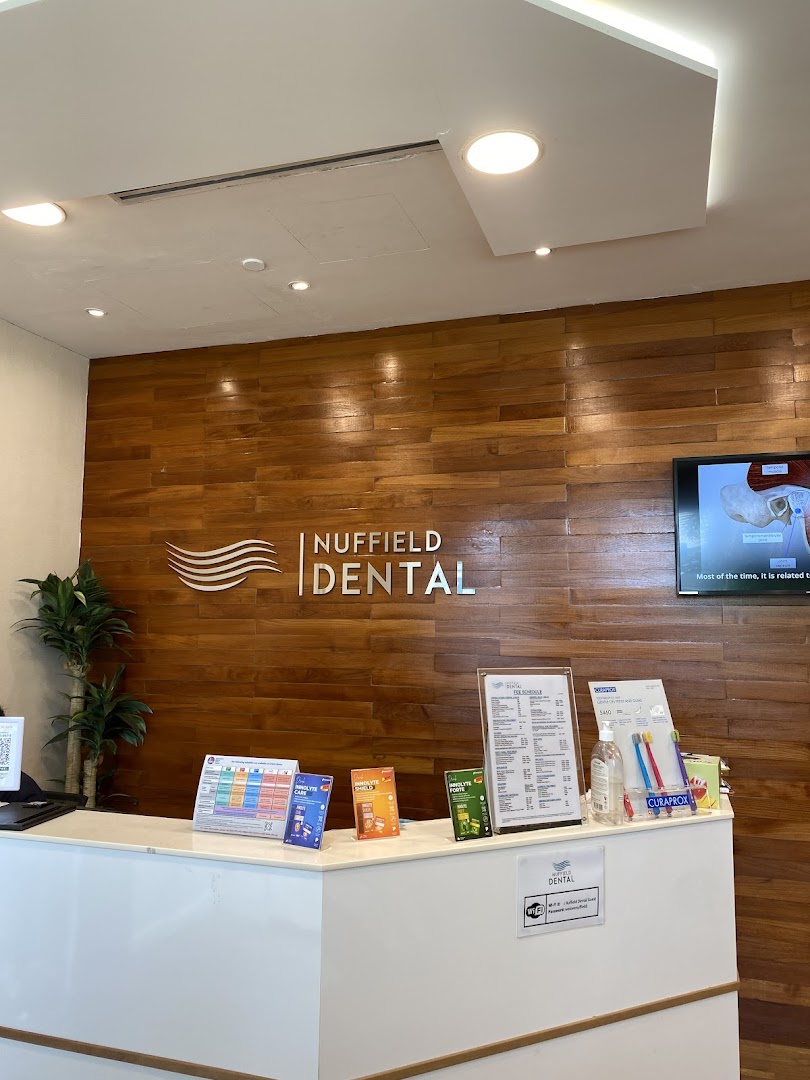 The modern reception desk of Nuffield Dental with a wooden feature wall.