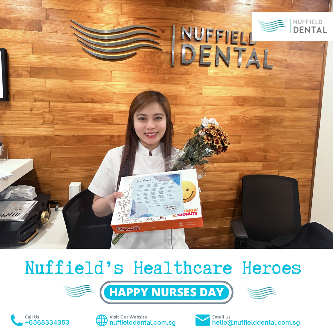 A smiling Nuffield Dental staff member holds flowers and a gift box in the clinic.