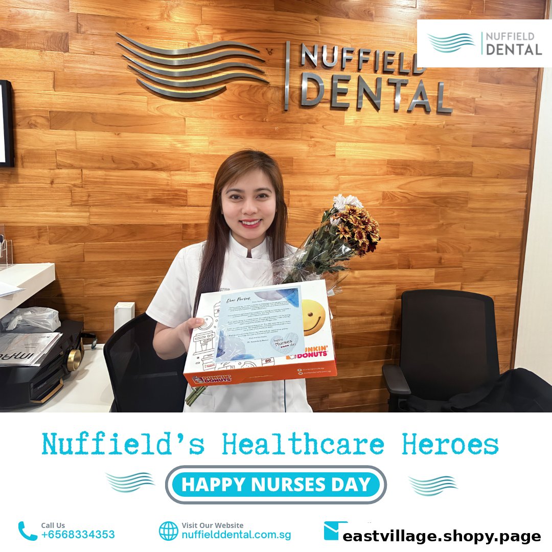 A smiling Nuffield Dental staff member holds flowers and a gift box in the clinic.