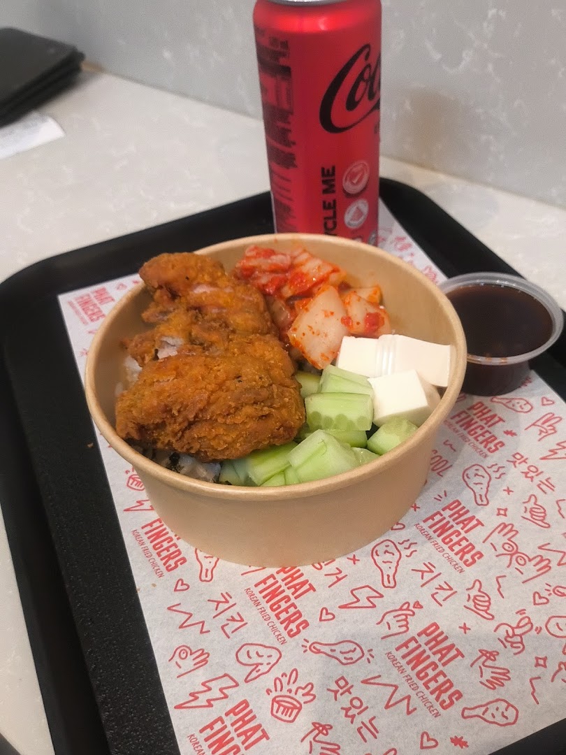A delicious Korean fried chicken rice bowl with kimchi, cucumber, and a Coca-Cola on a tray.