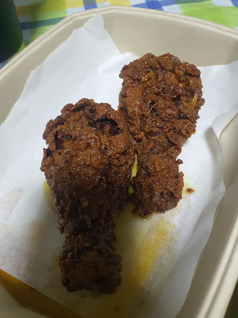 Two pieces of crispy, sauced Korean fried chicken in a takeout container.