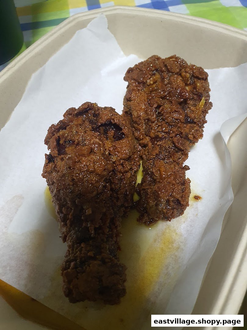 Two pieces of crispy, sauced Korean fried chicken in a takeout container.