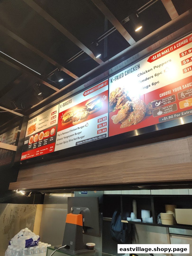 A digital menu board displaying Korean fried chicken, burgers, fries, and drink options with prices.