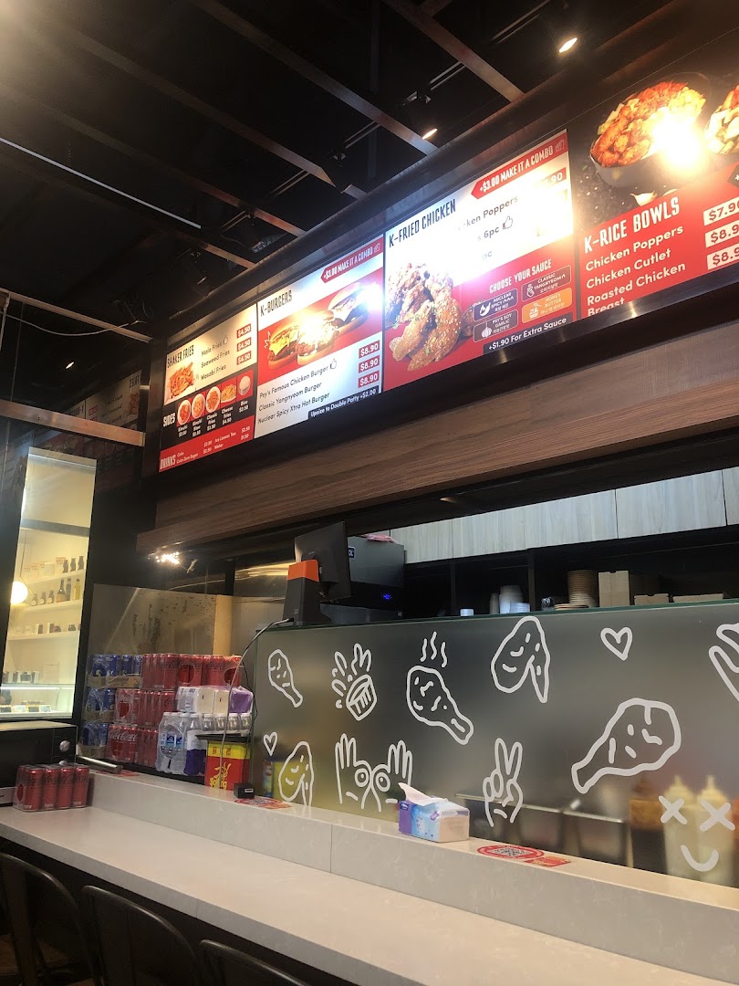 A vibrant digital menu board displaying Korean fried chicken, burgers, and rice bowls above a clean counter.