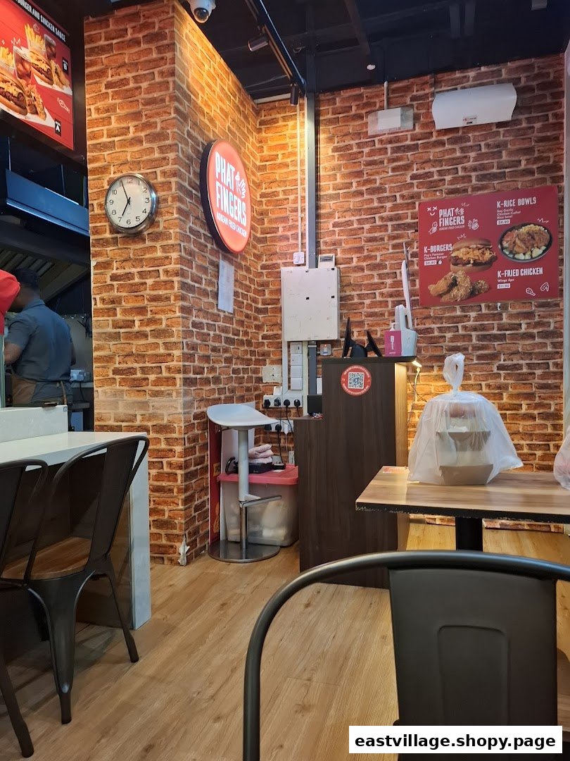 Interior view of Phat Fingers Korean Fried Chicken & Burgers, showing seating, brick walls, and menu boards.