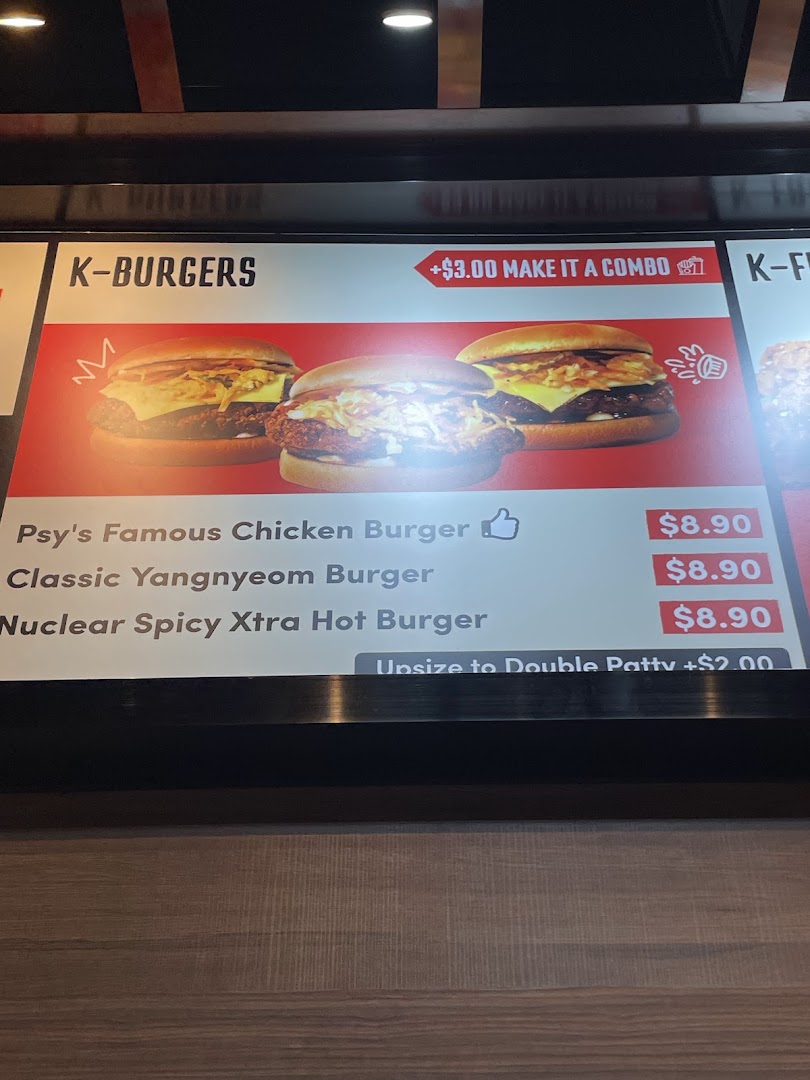A digital menu board displaying K-Burgers with various options and prices at Phat Fingers.