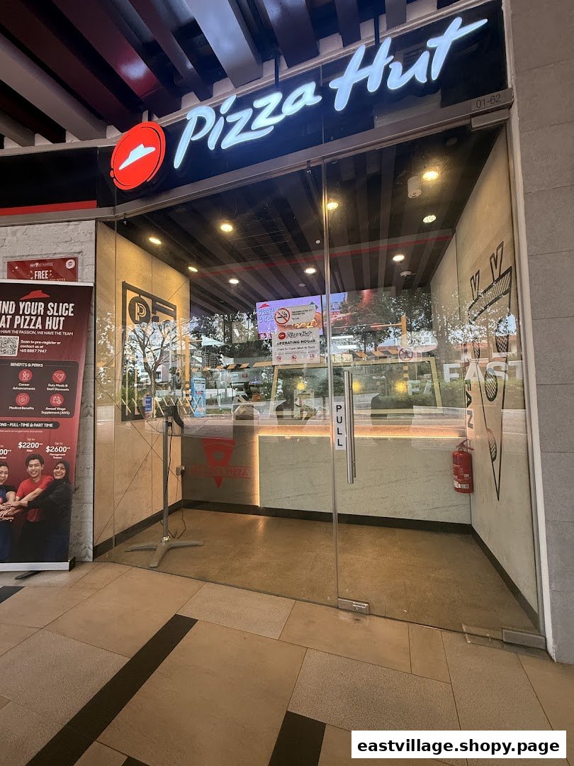 The inviting glass entrance of Pizza Hut, showcasing its prominent logo and a welcoming interior.