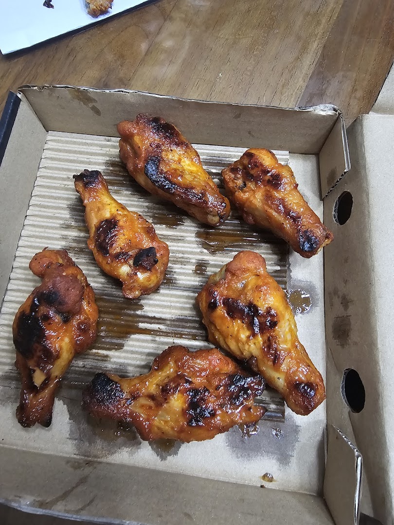 Six delicious, golden-brown chicken wings, likely from Pizza Hut, served in a cardboard takeout box.
