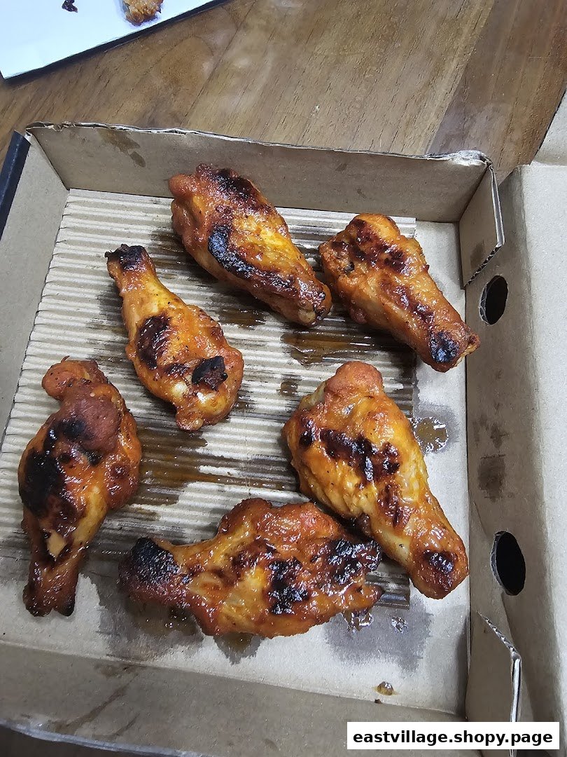 Six delicious, golden-brown chicken wings, likely from Pizza Hut, served in a cardboard takeout box.