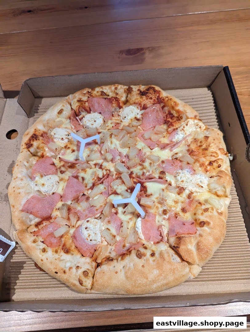 A freshly baked Pizza Hut pizza with ham, pineapple, and cheese in a cardboard box.