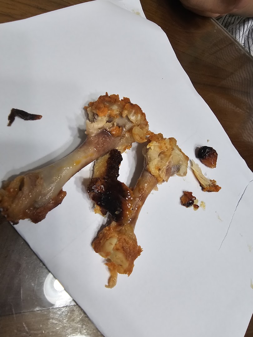 Close-up of discarded chicken bones and food remnants on a white paper after a meal.