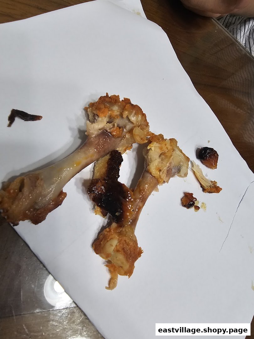 Close-up of discarded chicken bones and food remnants on a white paper after a meal.