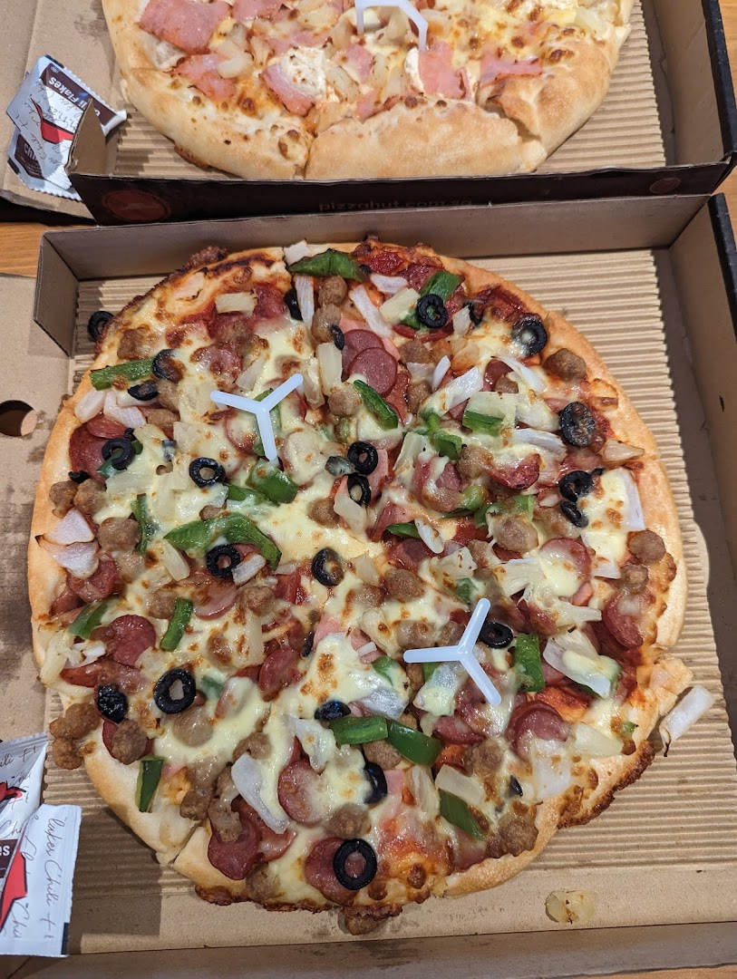 Two delicious pizzas in boxes, one loaded with various toppings, from Pizza Hut.