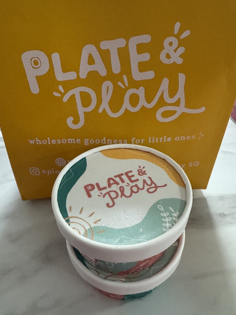 Branded containers and a shopping bag from Plate & Play, featuring wholesome goodness for little ones.