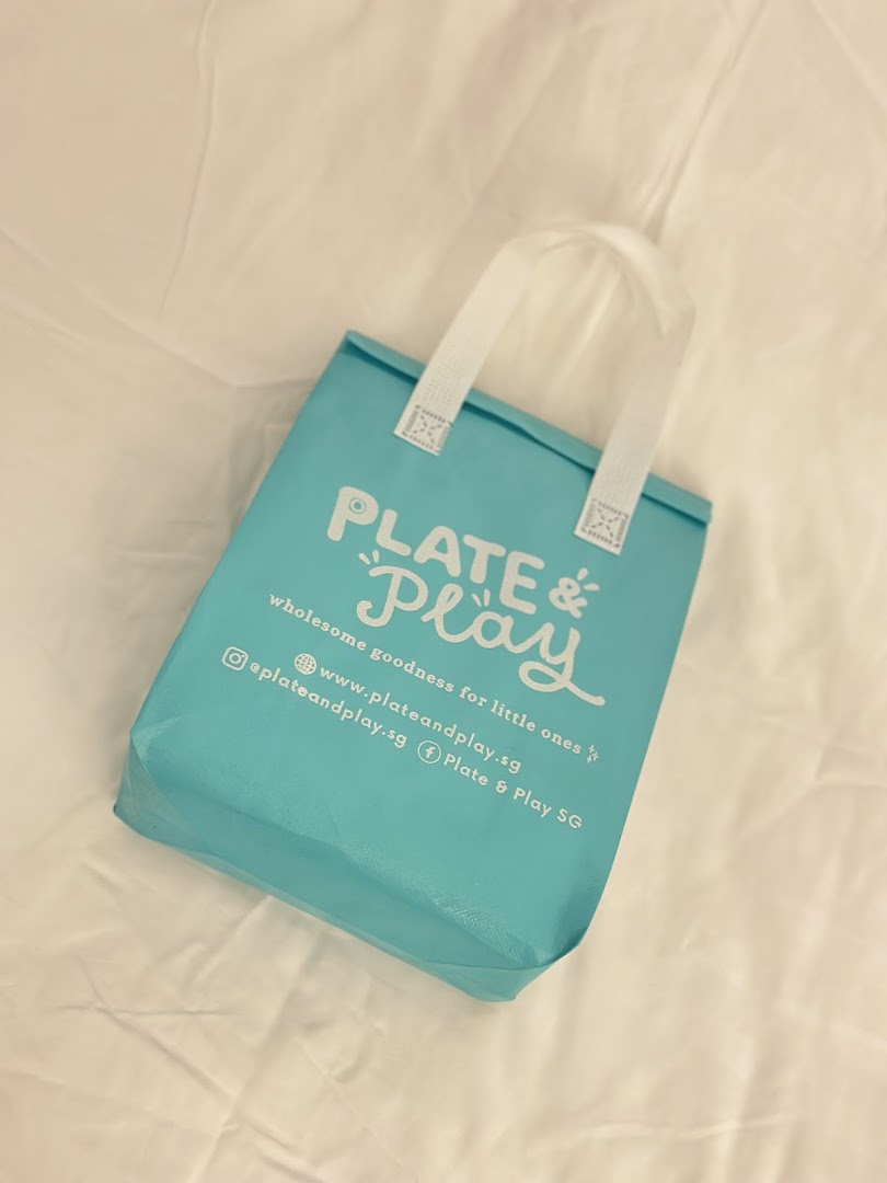 A light blue branded bag from Plate & Play, featuring their logo and slogan.