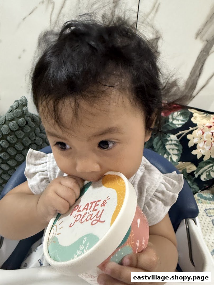 A baby holds a colorful 'Plate & Play' container, engaging with the brand's product.